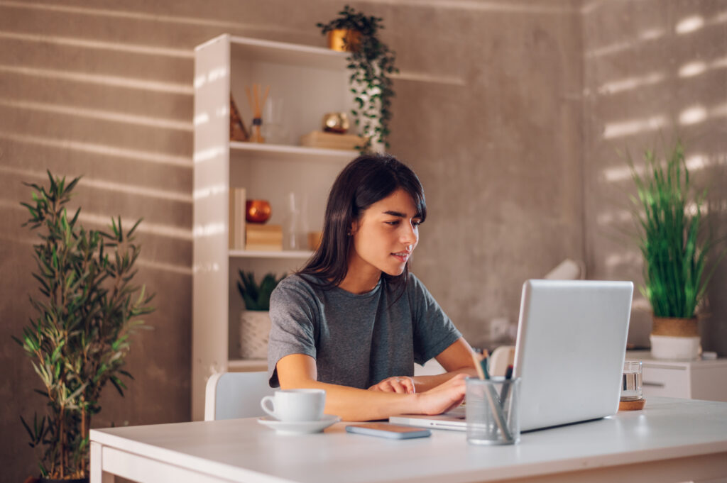 Side shot of a young businesswoman having an online meeting with her colleagues on the laptop. Looking curiously to the screen while listening to the new project ideas from her team mates. Copy space.